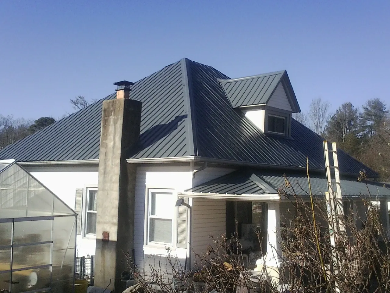 Dark blue standing seam metal roof on a white farmhouse with dormer — Slate & Tile Roof Repair by Roofing Brothers in Waterville